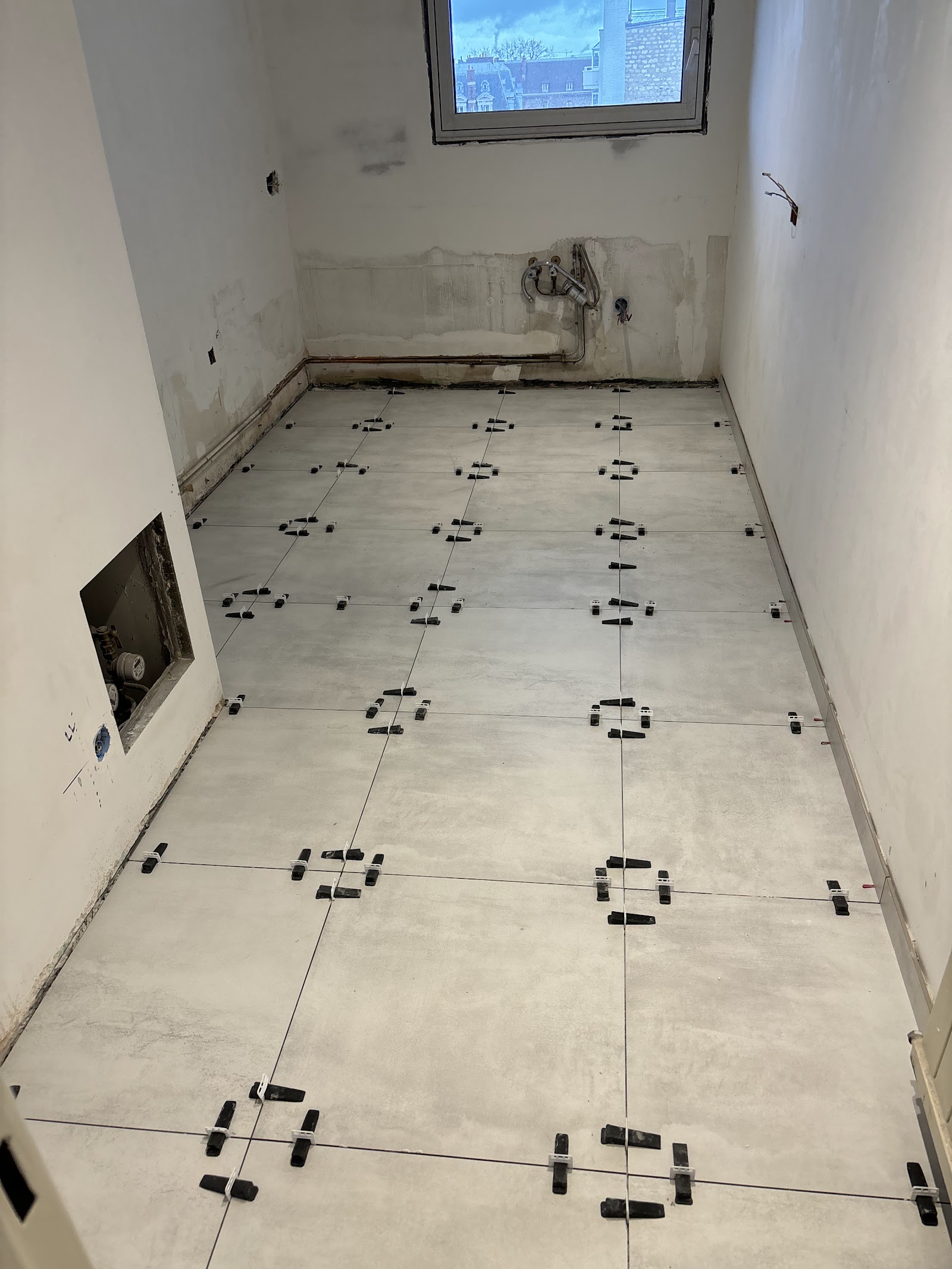 Pose de carrelage grand format en cours avec système de nivellement.