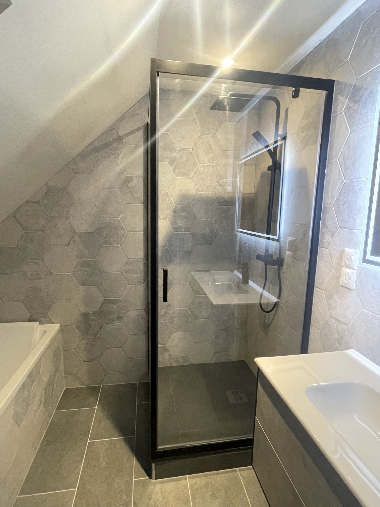 Douche à l'italienne mansardée avec carrelage hexagonal gris.