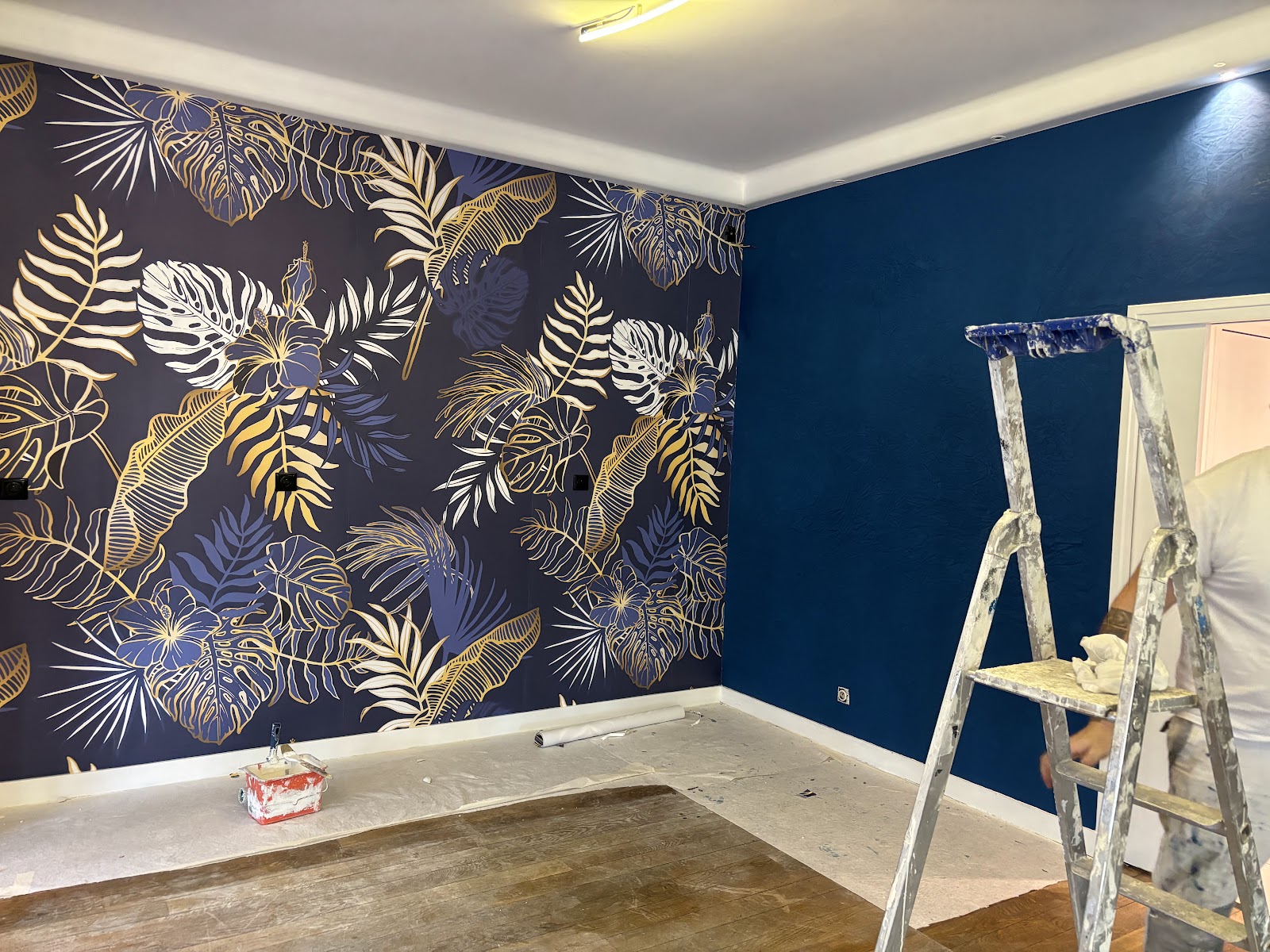 Pose d'un papier peint panoramique tropical et peinture bleu profond.